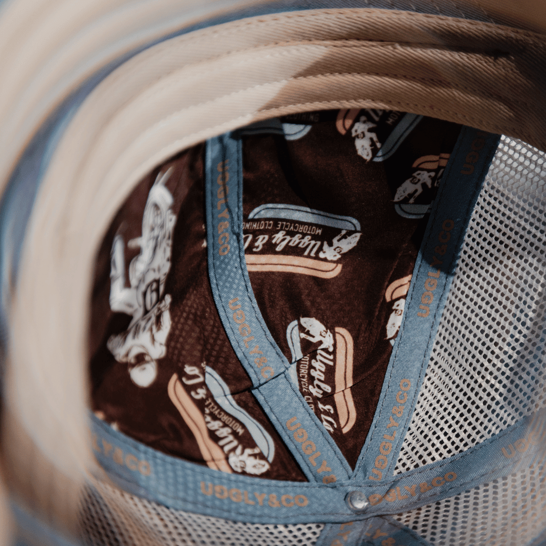 Dusty blue flat track trucker cap by Uggly and Co with mesh back and curved brim, stylish and casual outdoor hat.
