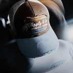Dusty blue Uggly and Co flat track trucker cap, adjustable hat with mesh back and curved brim for casual style.