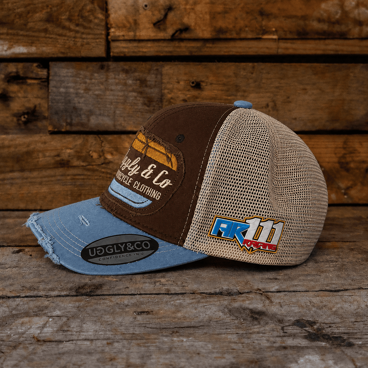 Dusty blue Uggly and Co flat track trucker hat with mesh back and curved brim, casual and stylish headwear.