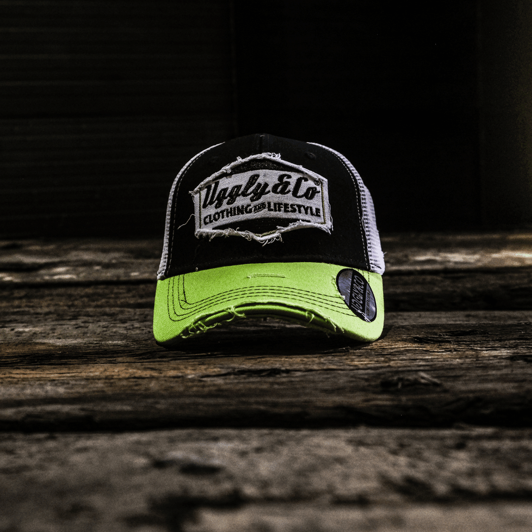 Yellow and white diamond-patterned Uggly and Co trucker cap with mesh back and curved brim.