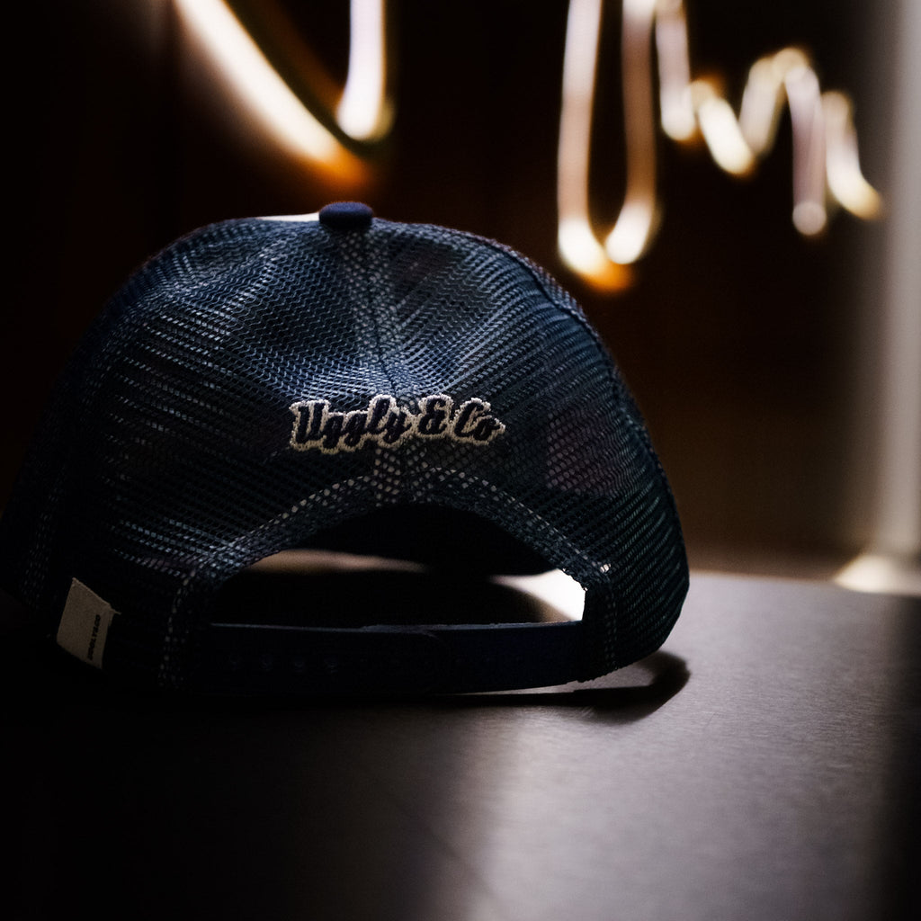 Navy blue and white diamond trucker cap by Uggly and Co with mesh back and logo on front panel.