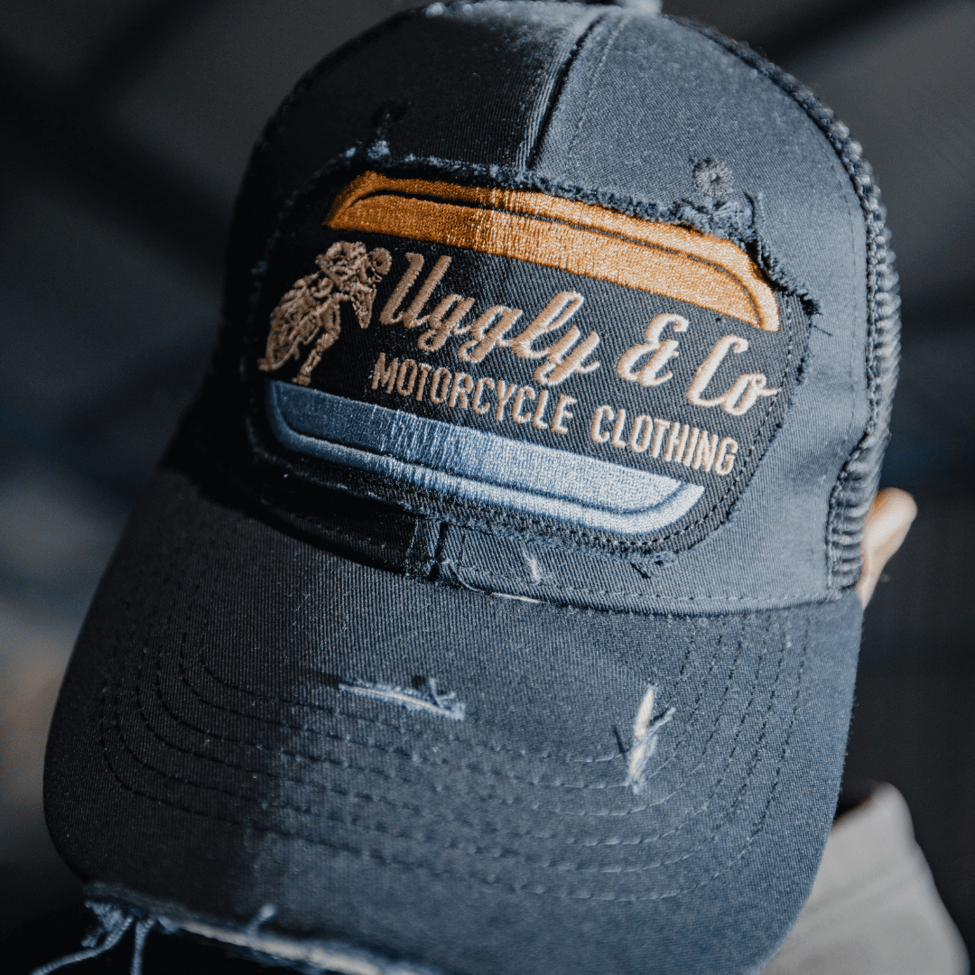 Vintage weathered black Uggly and Co flat track trucker cap with distressed fabric and classic mesh back.