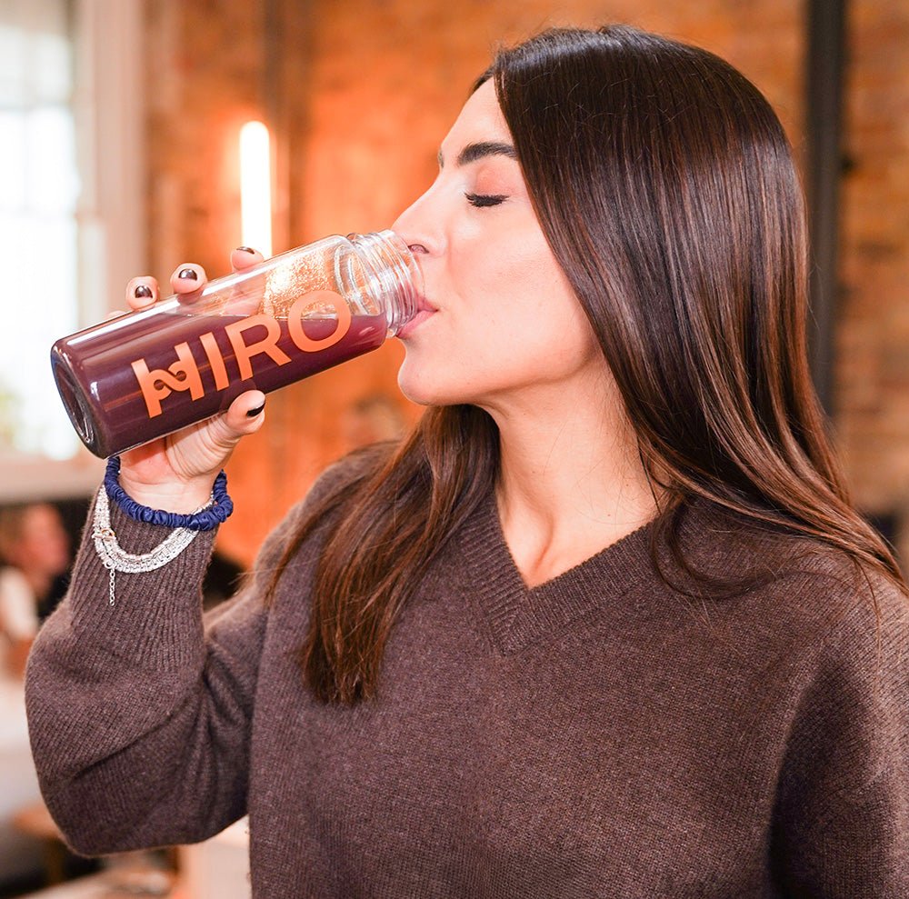 Woman holding the HIRO shaker, a sleek stainless steel accessory for mixing drinks, in a modern kitchen setting.